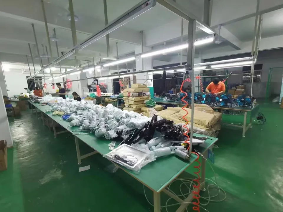 Fan assembly workstations with white fan bodies, parts and workers in the workshop.