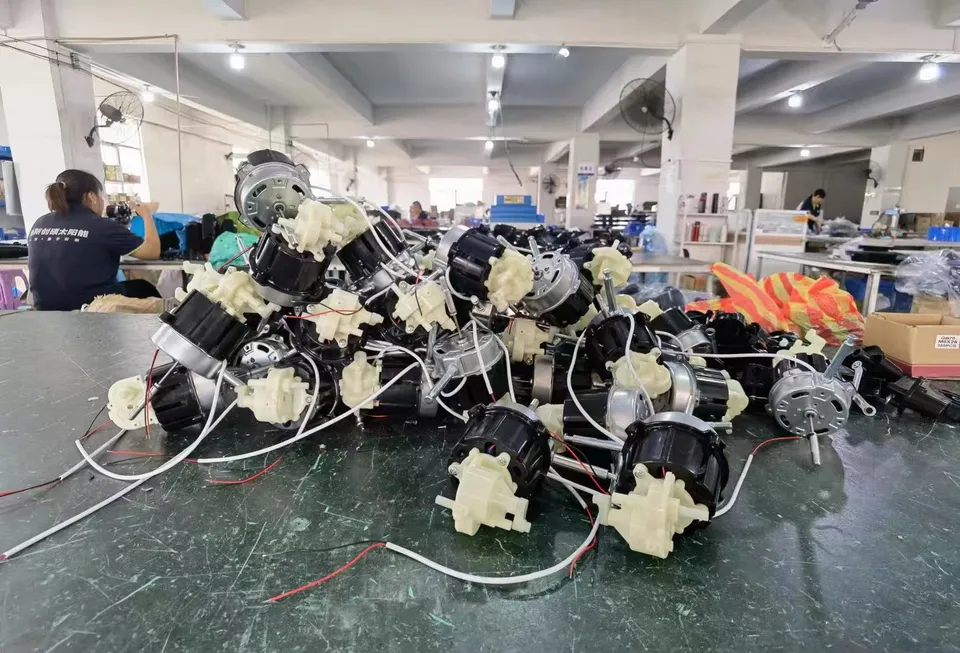 Fan motors, white gearbox housings and wire assemblies on a workshop table.