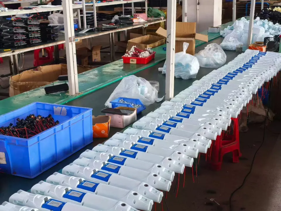 Rows of open white standing-fan bodies with internal components and wiring visible along an assembly bench.