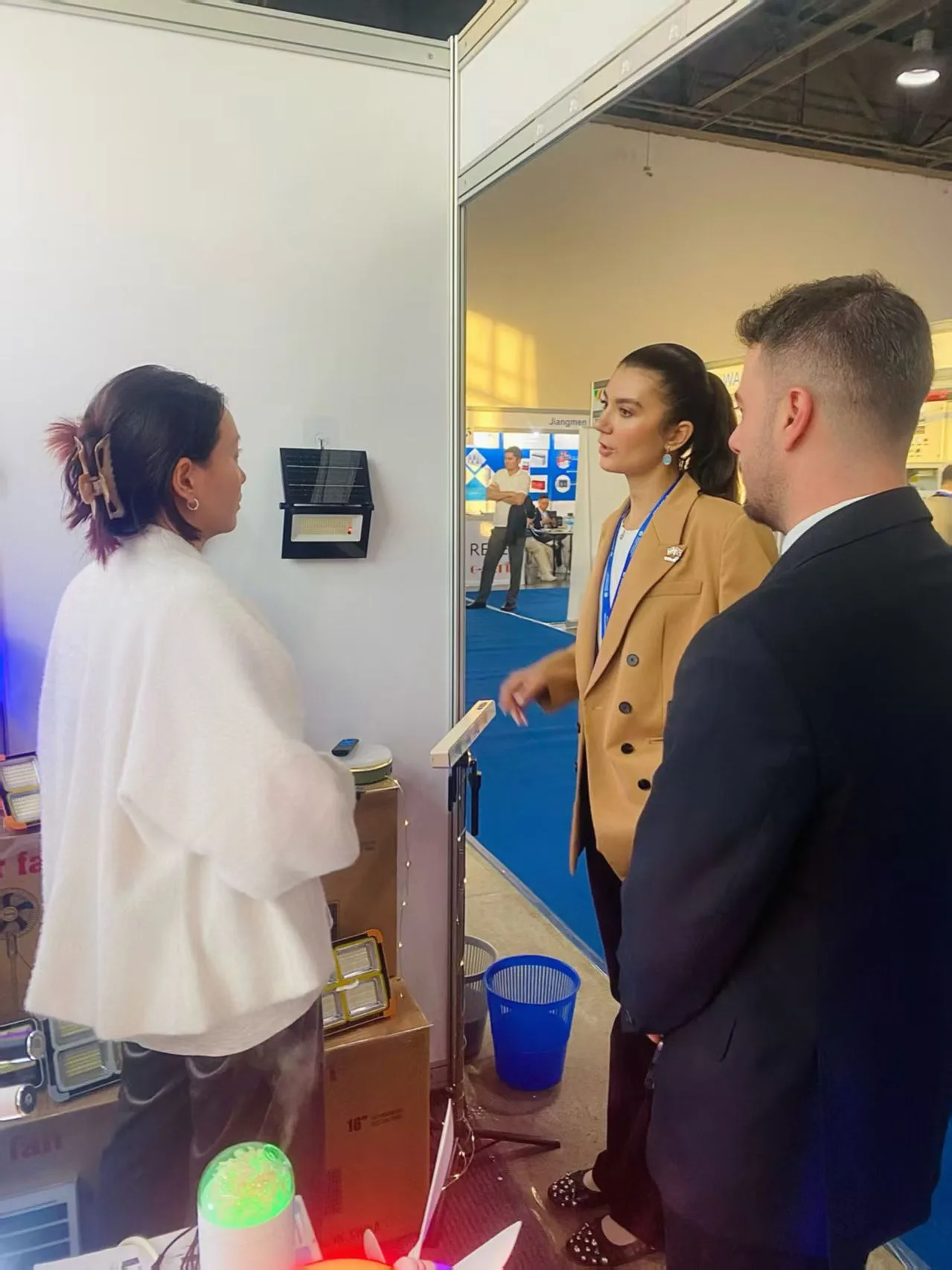 A Farseen representative speaking with visitors beside solar lighting products at the Uzbekistan exhibition